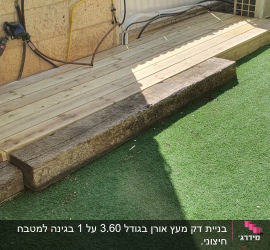 דק עץ ליד דשא סינתטי וגדר לבנה